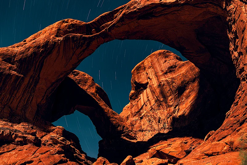 Long exposure night photograph of Double Arch in Arches National Park USA lit only by moonlight