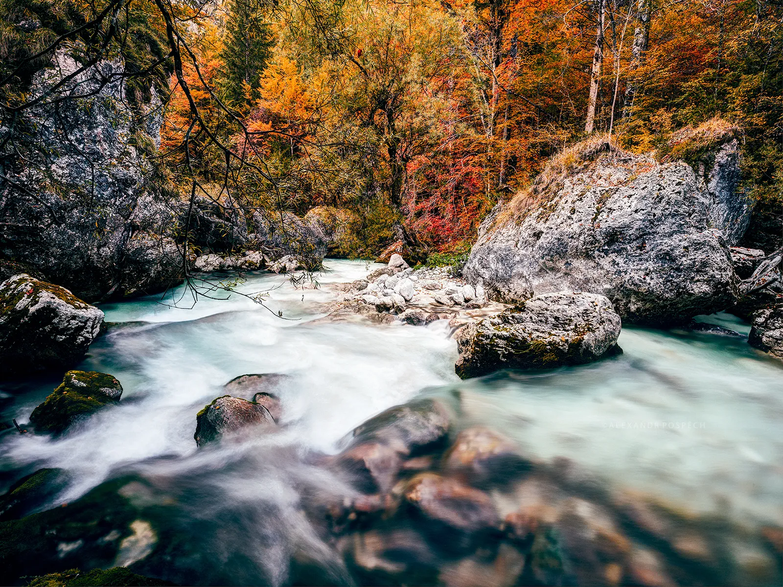 Soca River in Slovenia with bright turquoise water and autumn-colored trees around
